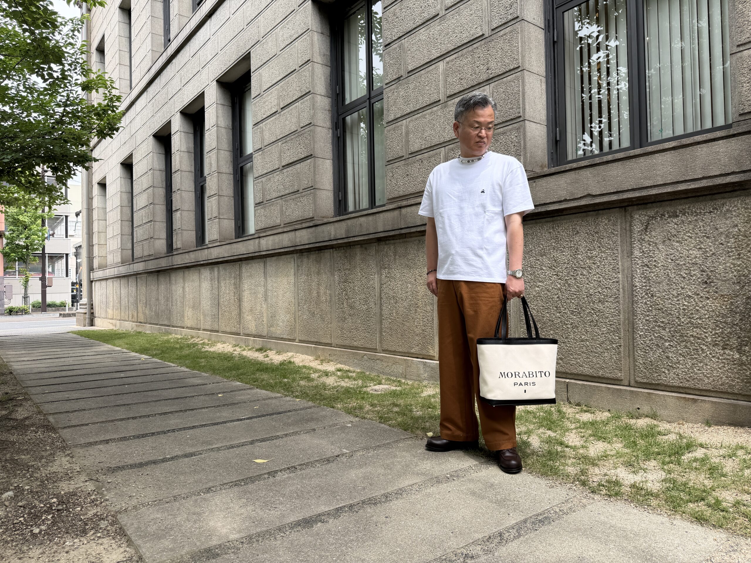 白Tシャツにブラウンパンツ、白のキャンバストートを合わせた大人の装い
